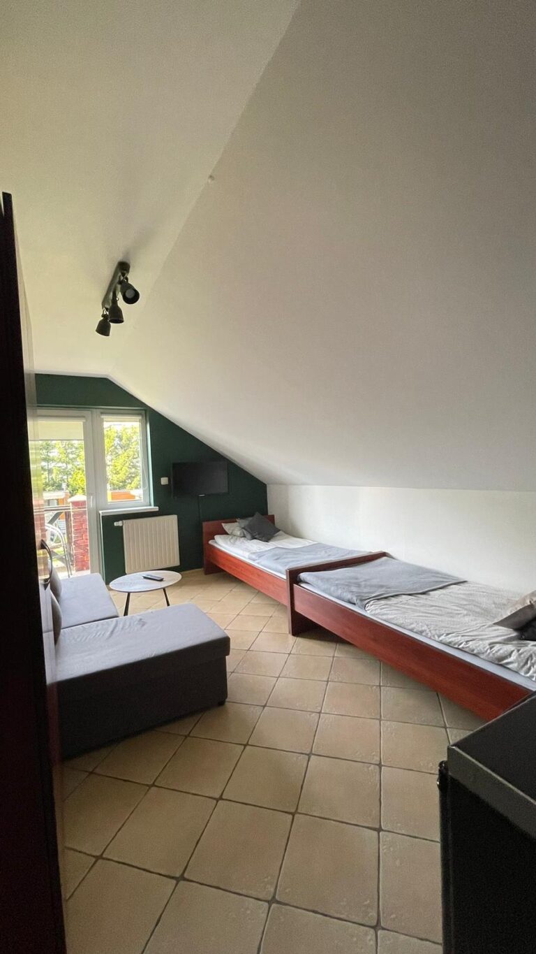 Łóżka pojedyncze, sofa i wyjście na balkon w pokoju Classic
