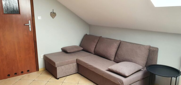 Sofa narożna i okrągły stolik pod skosem w pokoju Classic